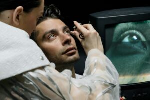 Close-up of a man having an eye examination with a monitor in the background.